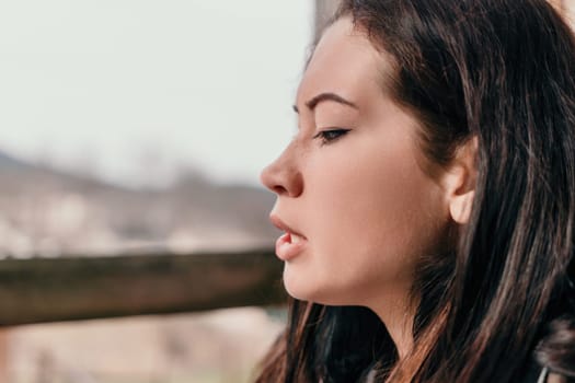 Happy young smiling woman with freckles outdoors portrait. Soft sunny colors. Outdoor close-up portrait of a young brunette woman and looking to the camera, posing against nature background.