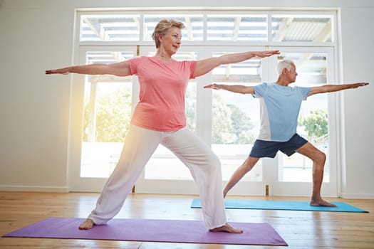 Yoga can add years to your life. Full length shot of a senior couple practicing yoga in their home