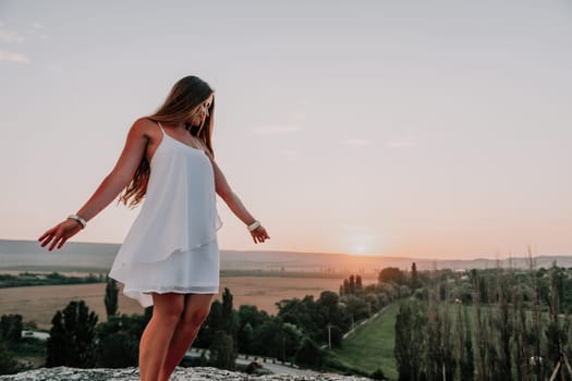 Romantic beautiful bride in white dress posing with sea and mountains in background. Stylish bride standing back on beautiful landscape of sea and mountains on sunset