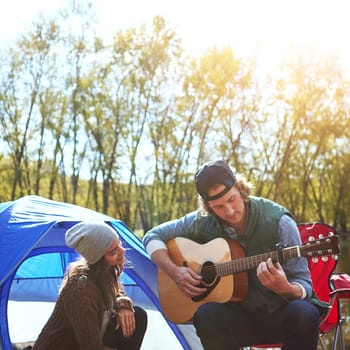 I just cant keep it to myself anymore. a young man playing his girlfriend a song on his guitar while out camping