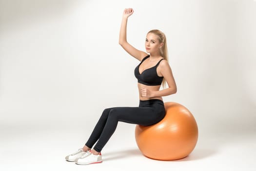 Young blonde woman training with fitball. she looks into the camera