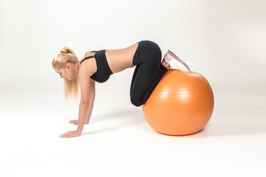 Young blonde woman training with fitball. Fitness exercises for abdomen