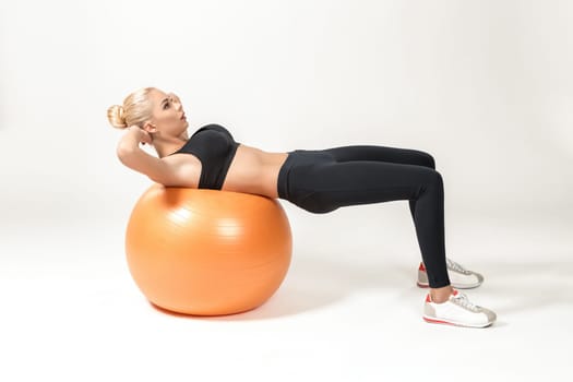 Young blonde woman training with fitball. Fitness exercises for abdomen