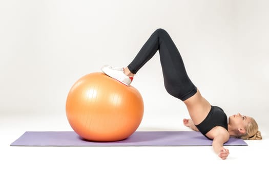 Young blonde woman training with fitball on the mat. Fitness exercises