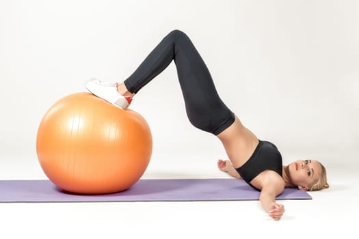 Young blonde woman training with fitball on the mat. Fitness exercises