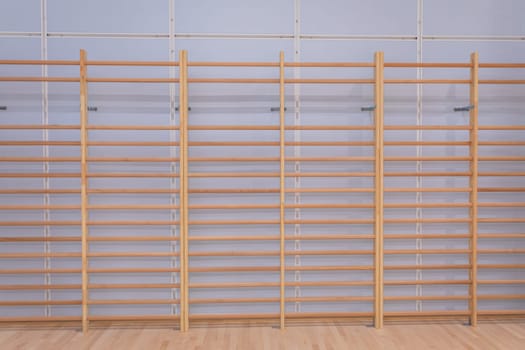 Essential equipment for any school sports hall. System gymnastic ladders made of wood and installed along the entire length of the wall.