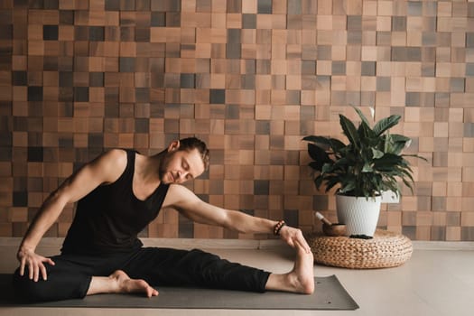 A man performing gymnastic exercises on a yoga mat at home.