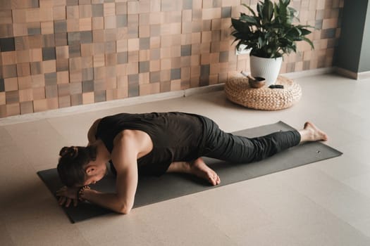 A man performing gymnastic exercises on a yoga mat at home.