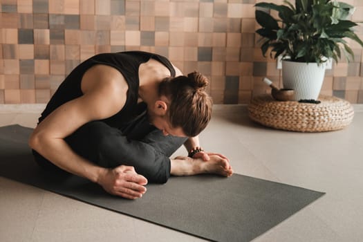 A man performing gymnastic exercises on a yoga mat at home.