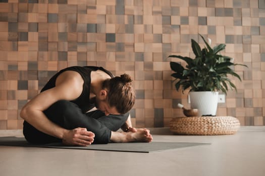 A man performing gymnastic exercises on a yoga mat at home.