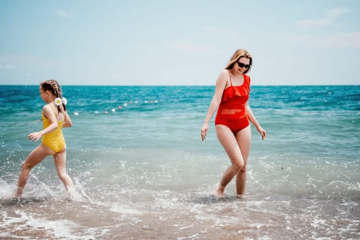 Happy loving family mother and daughter having fun together on the beach. Mum playing with her kid in holiday vacation next to the ocean - Family lifestyle and love concept.