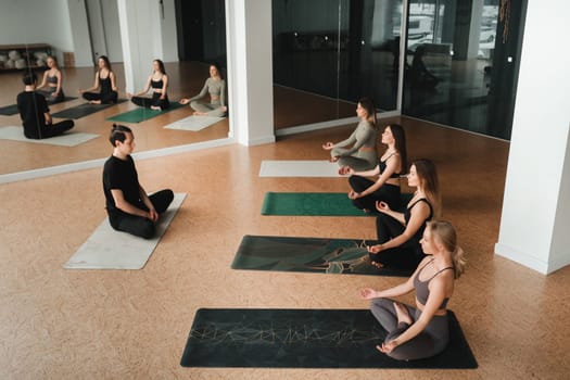 a group of girls do yoga in the gym under the guidance of a coach.