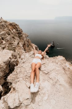 Woman travel sea. Happy tourist in hat enjoy taking picture outdoors for memories. Woman traveler posing on the beach at sea surrounded by volcanic mountains, sharing travel adventure journey