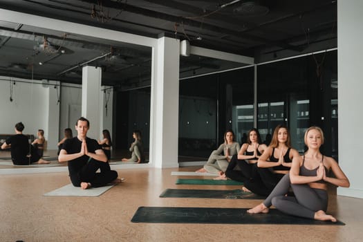 a group of girls do yoga in the gym under the guidance of a coach.