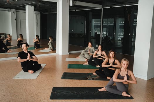 a group of girls do yoga in the gym under the guidance of a coach.