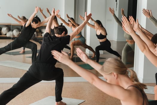 a group of girls do yoga in the gym under the guidance of a coach.