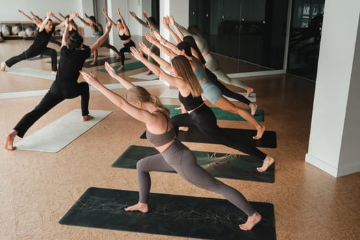 a group of girls do yoga in the gym under the guidance of a coach.