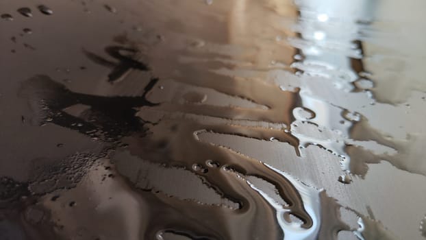 Water drops on black plastic. Surface with wet background. Abstract texture and pattern full of water. Raindrops of rain for overlaying on window with partial focus. Concept of autumn weather