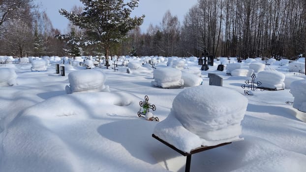 Ukrainian traditional cemetery in winter snow. Many of unmarked and faceless gravestones and crosses with forest in background. Graves in Russia after war