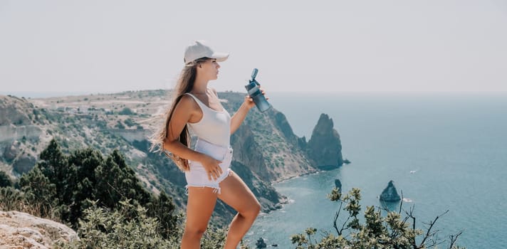 Woman travel sea. Young Happy woman in a long red dress posing on a beach near the sea on background of volcanic rocks, like in Iceland, sharing travel adventure journey