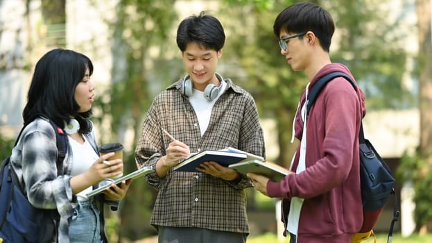 Group of students are talking to each other after classes while walking outdoors in university. Education and youth lifestyle concept.