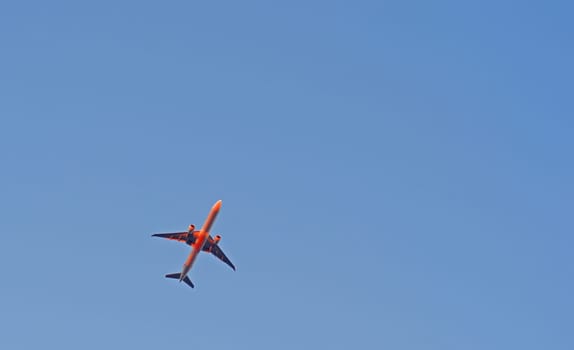 The passenger airplane is flying far away in blue sky