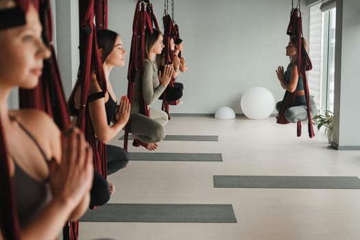 A group of women do yoga on hanging hammocks. Fly yoga in the gym.