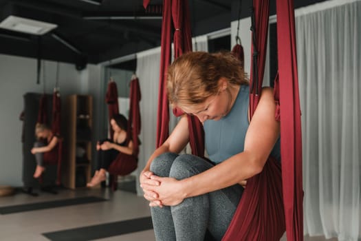 A group of women play sports on hanging hammocks. Fly yoga in the gym.