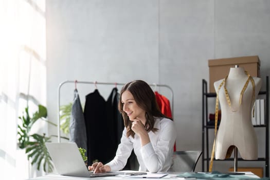 Responding on business e-mail. Beautiful young Fashion designer woman working using computer and smiling while siting in home.