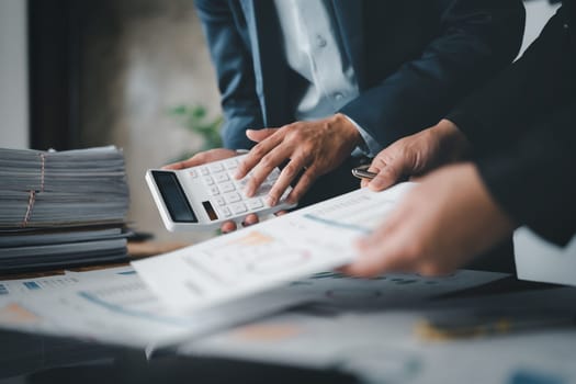 Accountant checking financial statement or counting by calculator income for tax form, Business woman sitting and working with colleague discussing the desk in office. Audit concept.