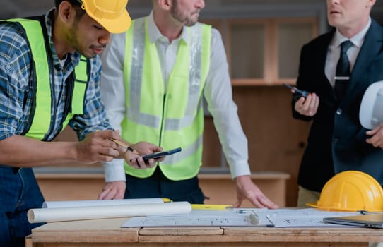 multi ethnic engineer brainstorming and measuring for cost estimating on paperworks and floor plan drawings about design architectural and engineering for houses and buildings.