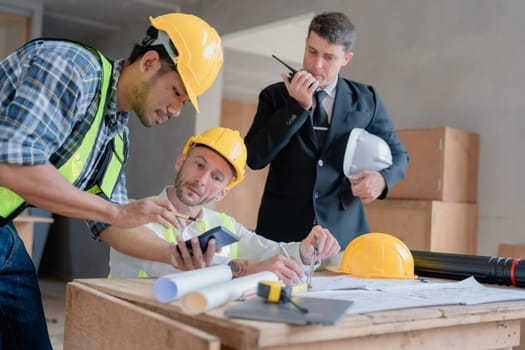 multi ethnic engineer brainstorming and measuring for cost estimating on paperworks and floor plan drawings about design architectural and engineering for houses and buildings.