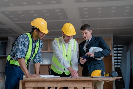 multi ethnic engineer brainstorming and measuring for cost estimating on paperworks and floor plan drawings about design architectural and engineering for houses and buildings.