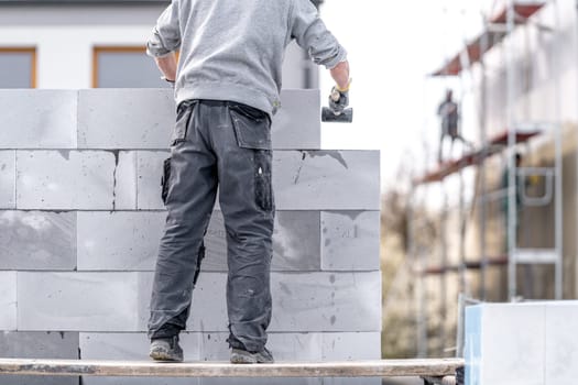 a mason builds the wall of a building from concrete bricks and blocks. High quality photo