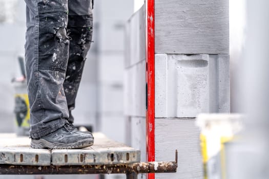 leveling bricks with the help of a spirit level during the construction of the wall of the house.