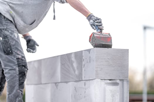 the mason applies glue to the concrete forms. construction of a wall of concrete bricks. High quality photo