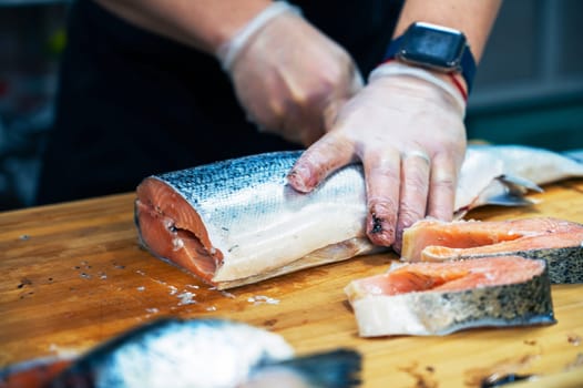 Chef preparing a salmon fish by gutting and filleting at the kitchen