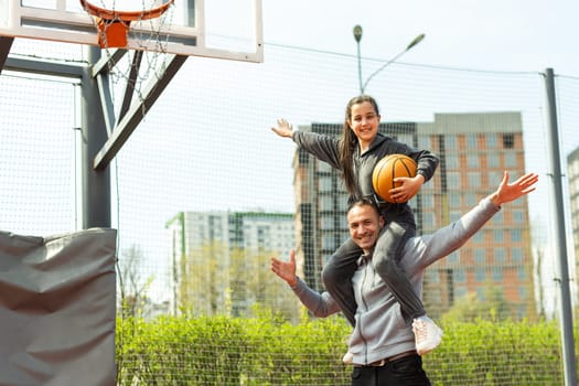 father and daughter playing basketball in the street.