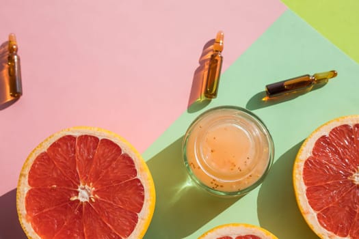 Ampules with vitamin C injection and orange fruit slices on color background