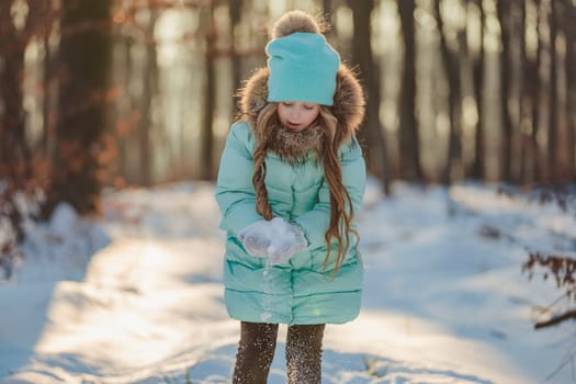 portrait of a girl against the backdrop of a winter forest illuminated by the sun