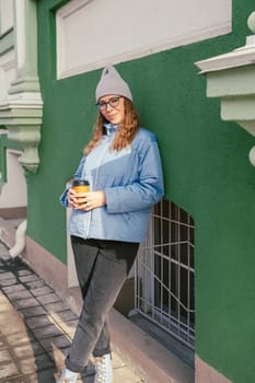 Portrait of a stylish woman in blue jacket with coffee cup. Spring outdoor portrait.
