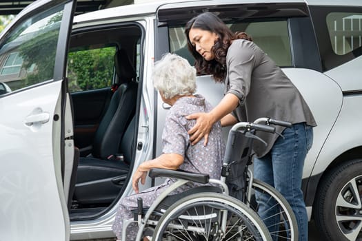 Caregiver help and support asian elderly woman sitting on wheelchair prepare get to her car to travel in holiday.