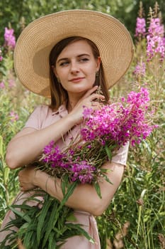 A young woman in nature with a bouquet of pink wild flowers. A bouquet of Ivan-tea in the hands of a woman.