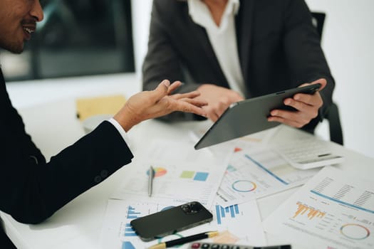 Two business men meeting to talking or discuss marketing work in workplace using paperwork, calculator, computer to work