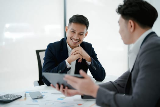 Two business men meeting to talking or discuss marketing work in workplace using paperwork, calculator, computer to work