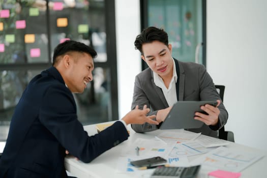 Two business men meeting to talking or discuss marketing work in workplace using paperwork, calculator, computer to work