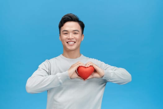 Young man holding a red heart shaped toy