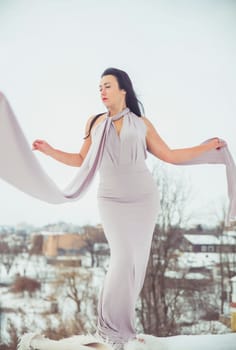 Attractive woman in evening dress on a hill in winter.