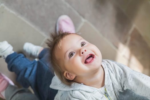 beautiful toothless baby leaned back holding mom's hands.