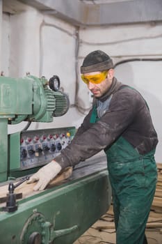 Skvira, Ukraine, March 2018: worker in a factory passes boards through a jointer